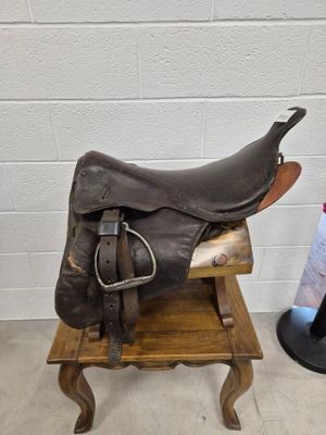 une selle de cheval posée sur un support en bois à côté d'un porte-revues