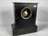 a small black clock with a gold bell on it