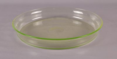 un bol transparent à bord vert posé sur une surface blanche
