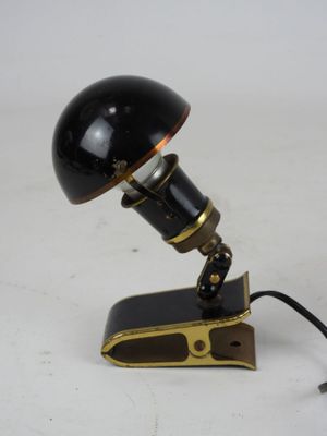 an image of a black lamp with a gold base on a white surface