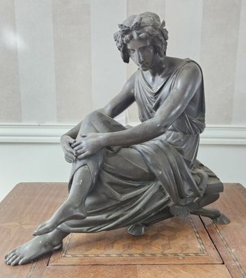 statue d'une femme assise sur une table en bois, les mains posées sur les genoux