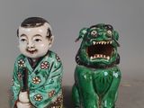 deux figurines asiatiques représentant un garçon et un chien sur un fond gris