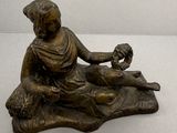 statue en bronze représentant une femme assise sur un rocher, tenant un oiseau dans la main