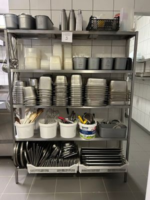 many plates and pans on a metal shelf in the kitchen