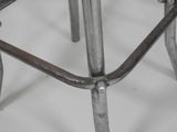a close up of a metal stool on a white surface