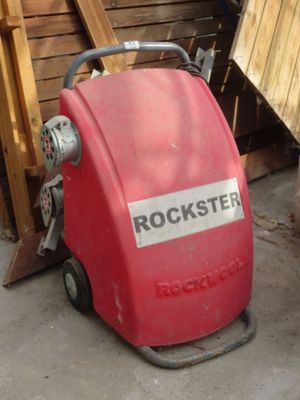a red machine that is sitting in front of a pile of wood
