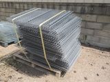 une pile de filets de gabions posée sur une palette devant un mur de briques