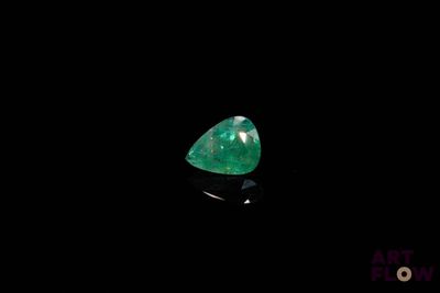 a close up of a green emerald stone on a black surface