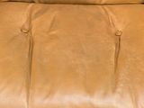 brown leather lounge chair with black metal legs and foot rests on carpet