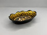 black and yellow bowl with figures on it sitting on a table