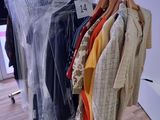 des vêtements suspendus à un portant dans un magasin de vêtements, près d'une vitrine
