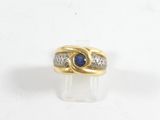Gros plan sur une bague en or ornée d'une pierre bleue