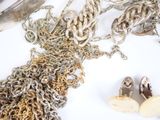 a pile of silver chains and a pair of shoes next to a pair of scissors