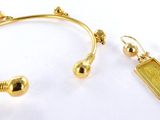 deux paires de boucles d'oreilles en or et un bracelet posés sur un fond blanc