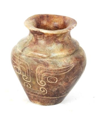 un vase brun orné d'un motif sur une surface blanche