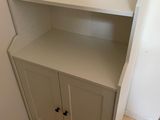 a small white cabinet with a mirror in the corner