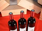 three bottles of wine sitting on a red table cloth