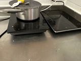 une casserole et une poêle posées sur la plaque de cuisson d'une cuisine