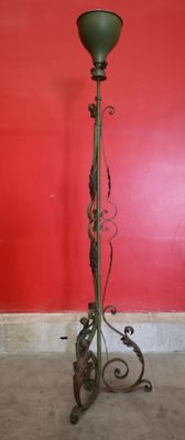 an antique floor lamp stands in front of a red wall