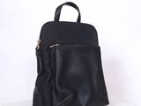 un sac à dos en cuir noir posé sur une étagère blanche