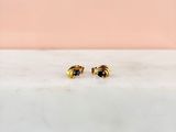 un gros plan sur une paire de boucles d'oreilles en or posées sur une surface en marbre
