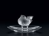 un oiseau en verre posé sur une assiette en verre