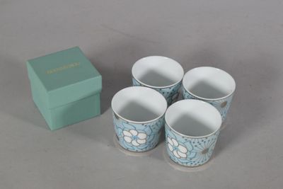 quatre tasses posées à côté d'une boîte sur une table