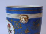 a blue cup with gold trim and a flower design on it