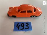 une petite voiture orange à côté d'une feuille de papier bleue
