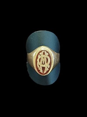 une image représentant une bague dorée et bleue ornée d’un monogramme