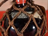 rope wrapped around a bottle of wine on a red surface