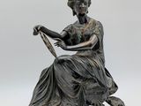 statue en bronze représentant une femme assise sur une chaise, un livre à la main