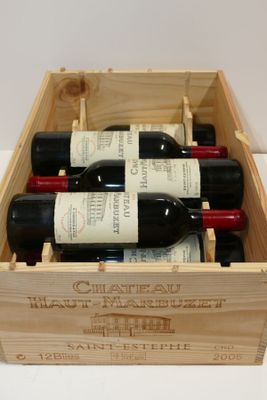 des bouteilles de vin rouge dans une caisse en bois posée sur une surface blanche