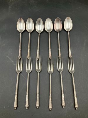 six spoons and a fork are lined up on a table