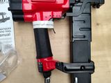 a red and black stapler sitting on a table next to a plastic bag