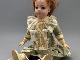 an image of a doll sitting on the ground with a toothpick in her hand
