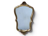 une image d'un miroir encadré d'or sur un mur blanc