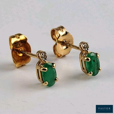 une paire de boucles d'oreilles à clous en émeraude et diamant sur un fond blanc