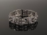 a close up of a diamond bracelet on a reflective surface