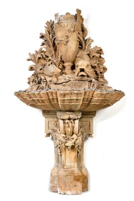 une sculpture en bois accrochée au mur, sur laquelle repose un vase