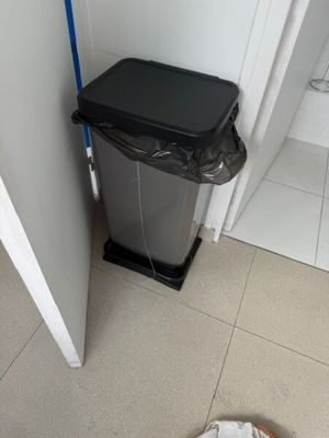 une poubelle dans un coin de la salle de bains, à côté d'une autre poubelle