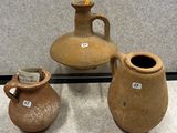 trois vases en argile, munis d'étiquettes, posés sur une table