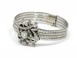a close up of a diamond and emerald bracelet on a white background