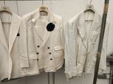 three white jackets hanging on a rack in a room