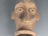 une sculpture en argile représentant le visage d'un homme, accrochée au mur