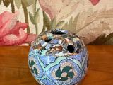 un petit vase posé sur une table, avec un coussin en arrière-plan