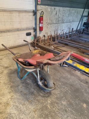 une brouette dans un garage, avec un extincteur en arrière-plan