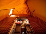 a bed in a tent with a red and white blanket