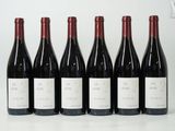 six bottles of red wine are lined up on a table