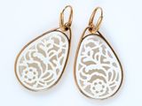 boucles d'oreilles dorées et blanches en forme de larme sur fond blanc